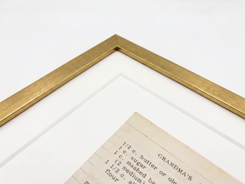 The corner of a gold frame over a handwritten recipe card.