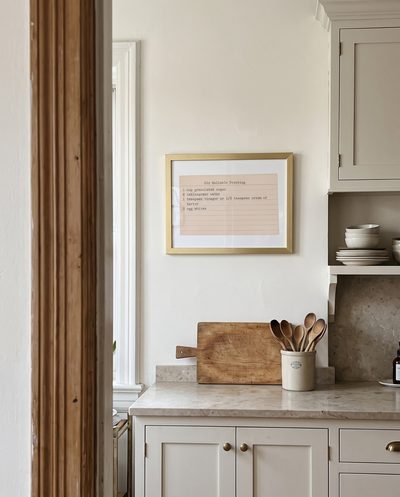 A typed Old Reliable Frosting card, framed in gold, on a kitchen wall above the counter.